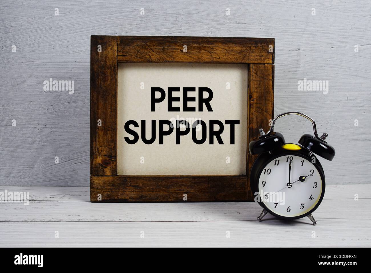 Testo di supporto peer con sveglia su sfondo in legno Foto Stock