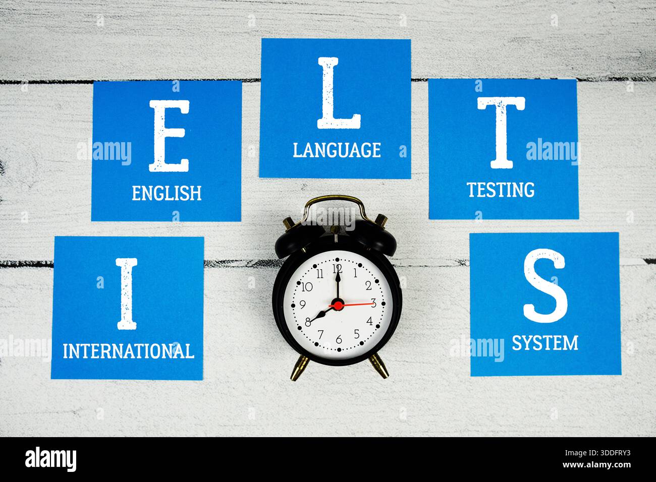 IELTS International English Language Testing System con sveglia su fondo in legno Foto Stock