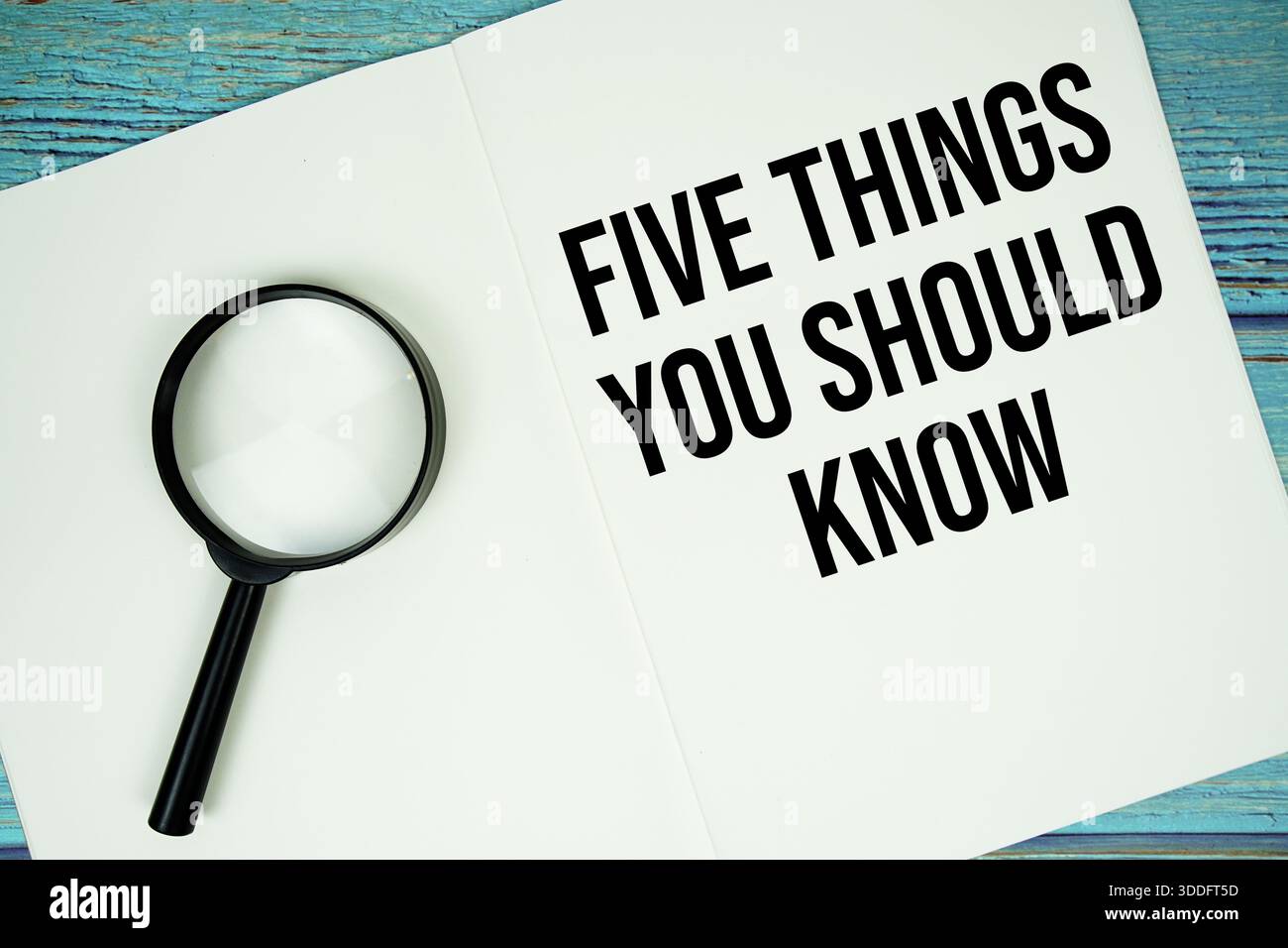 Cinque cose da sapere: Testo scritto su blocco note con lente d'ingrandimento piatta su sfondo in legno Foto Stock