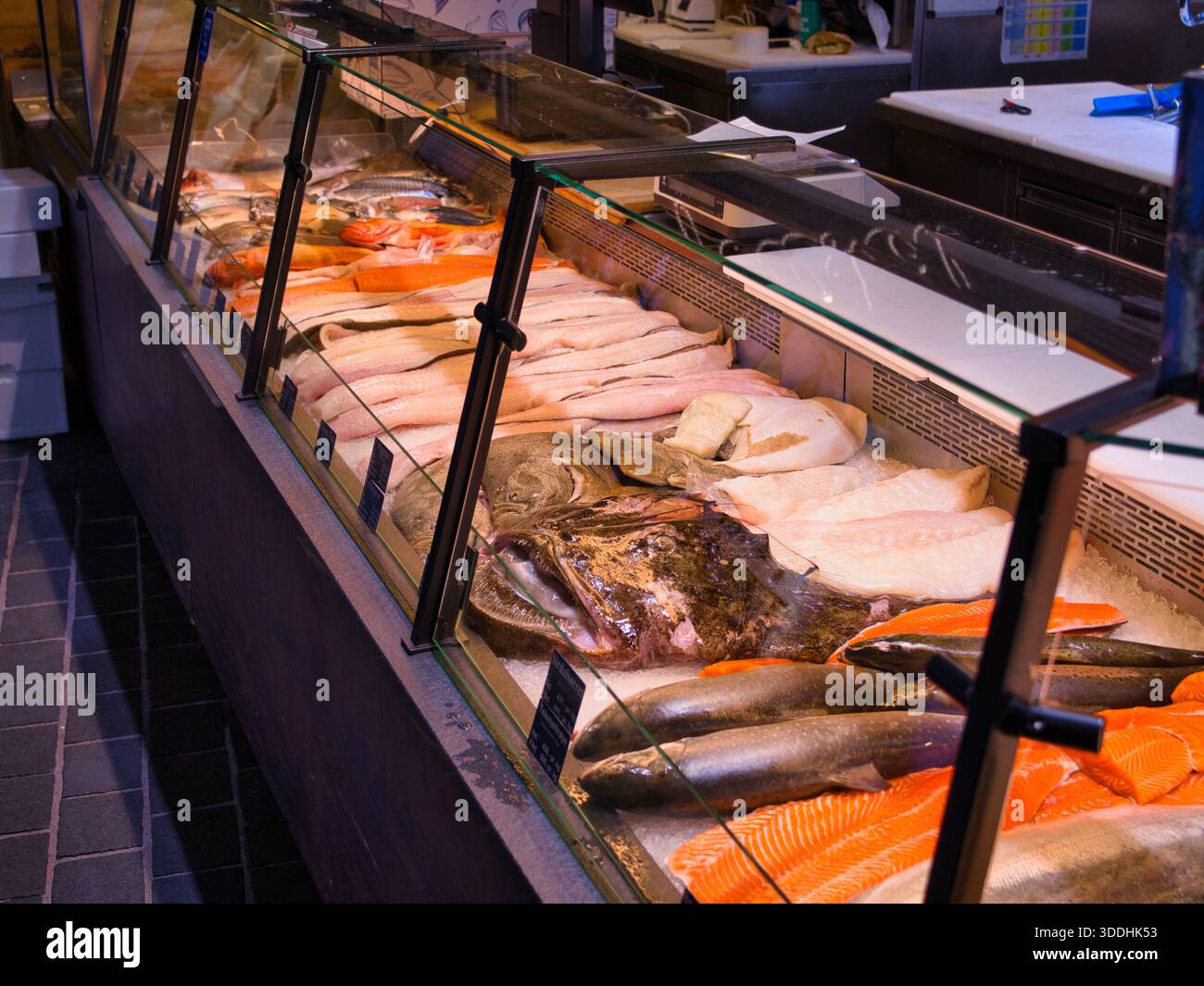Bergen, Norvegia - 13 novembre 2025: Filetti di pesce fresco e pesce intero su ghiaccio in un bancone refrigerato al mercato del pesce di Bergen, Bergen, Norvegia, con un aspetto vivace e appetitoso. Foto Stock