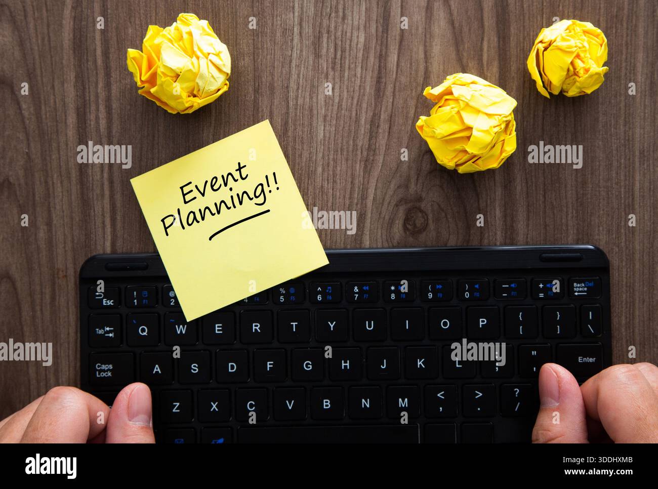 Persona che digita su una tastiera con appunti per la pianificazione degli eventi e carta sgualcita Foto Stock