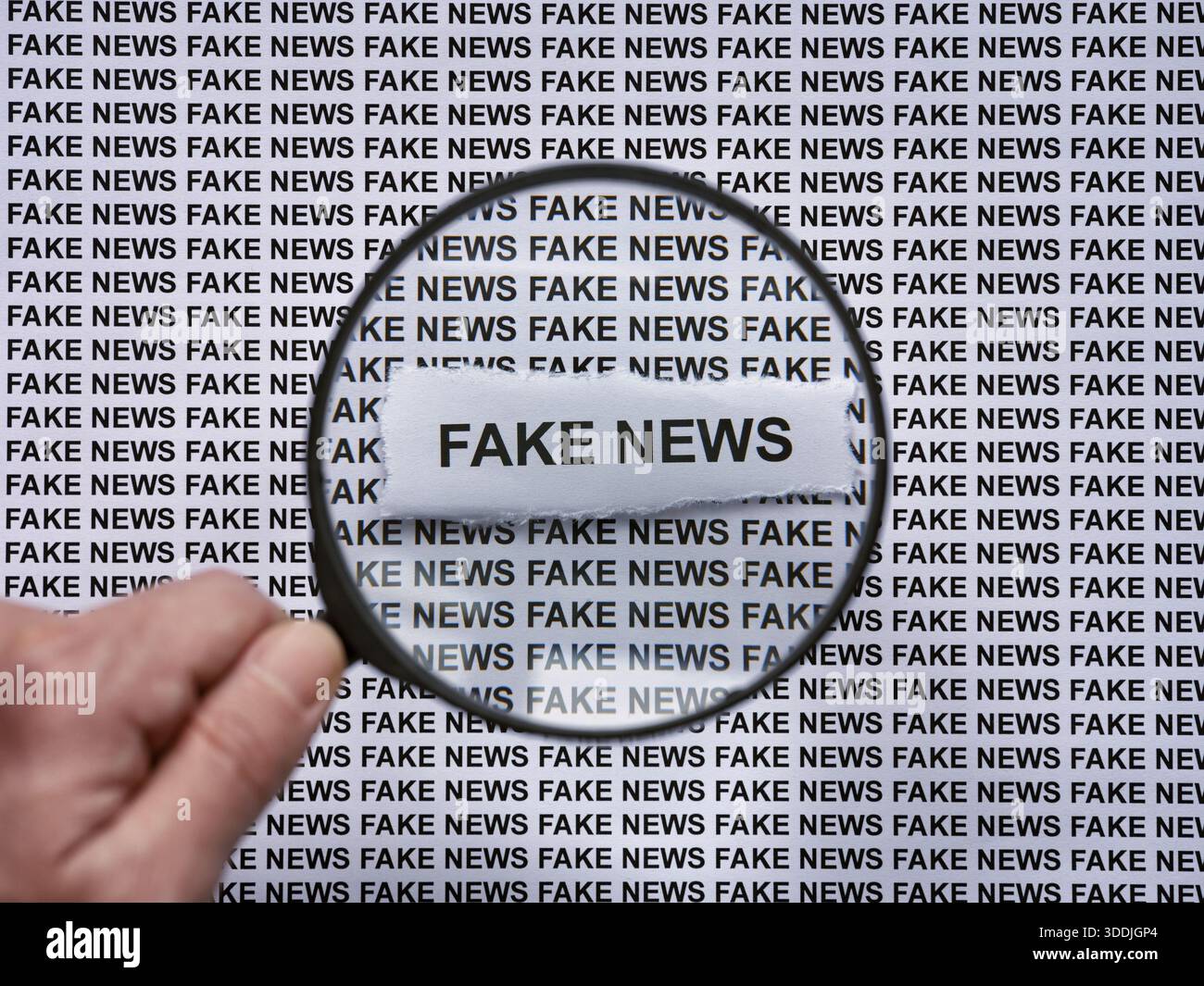 Una persona con una lente d'ingrandimento in mano che ingrandisce le parole Fake News sullo sfondo di una stampa di giornali. Primo piano. Foto Stock