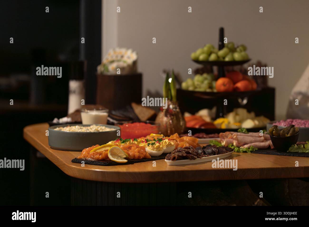 Buffet per eventi di lusso. Elegante buffet con salmone affumicato, affettati, uova diavolate e frutta fresca su un tavolo di legno. Foto Stock