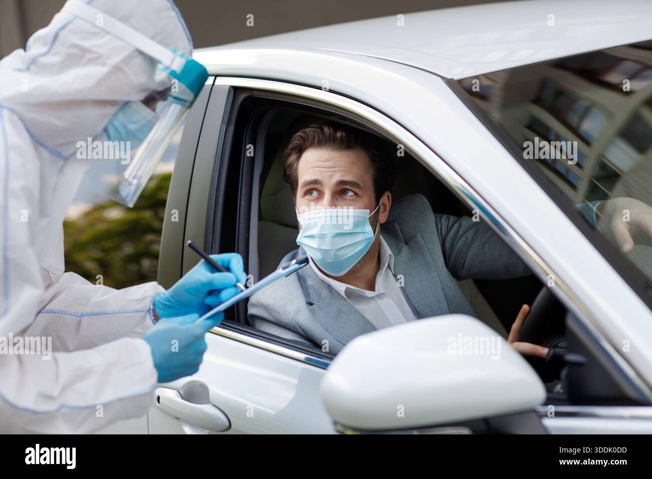 Controlla passeggeri e driver per virus, uomo in tuta biologica scrive dati su tablet, COVID-19 quarantena Foto Stock