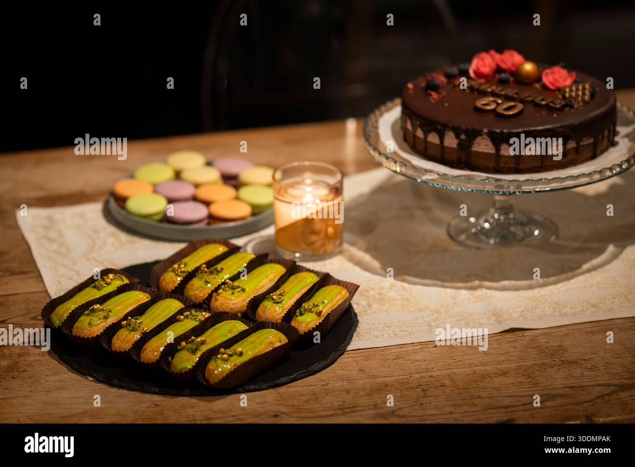 Éclair glassati di pistacchio serviti su un tavolo rustico a lume di candela in un elegante buffet di dessert. Spettacoli gourmet di pistacchio organizzati per un evento di lusso. Foto Stock