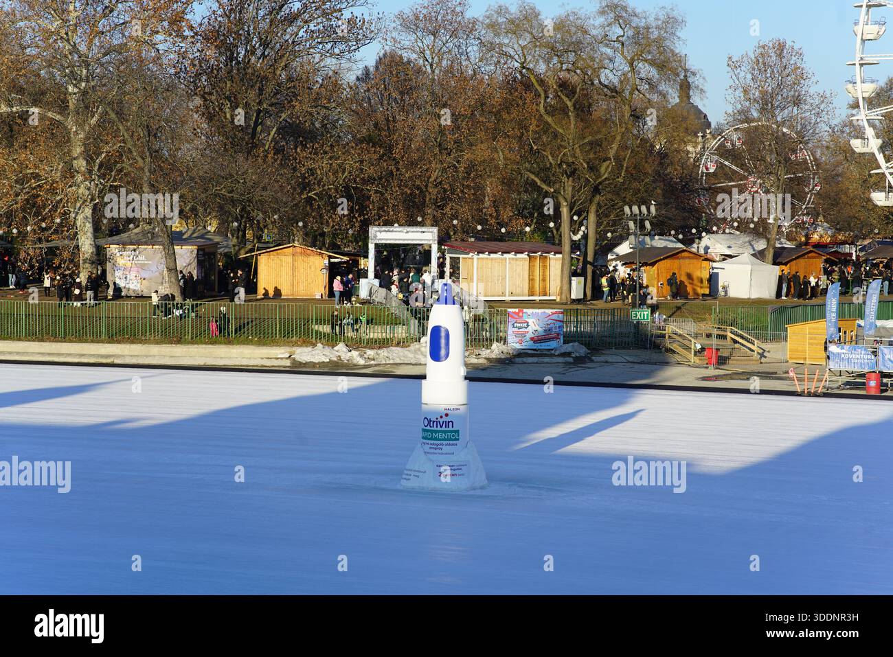 Segnalibro centrale su una pista di pattinaggio all'aperto con bancarelle e giostre invernali sullo sfondo.Budapest, Ungheria Foto Stock