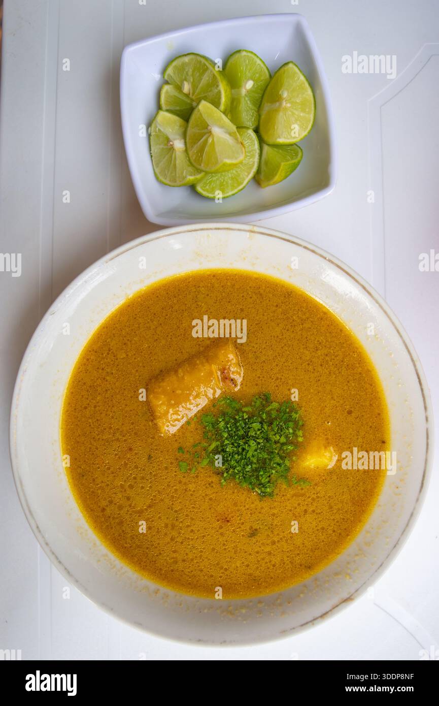 Tradizionale zuppa colombiana servita con lime e coriandolo, esaltando i sapori ricchi. Perfetto per la fotografia culinaria. Foto Stock