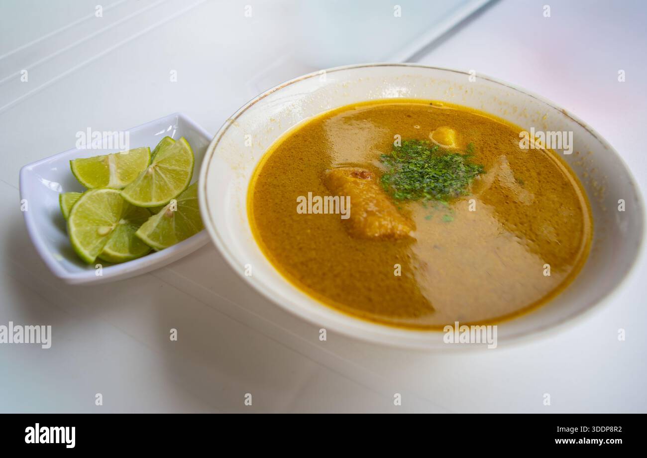 Una deliziosa ciotola di tradizionale zuppa di pesce colombiana servita con spicchi di lime, perfetta per mostrare la cucina colombiana. Foto Stock