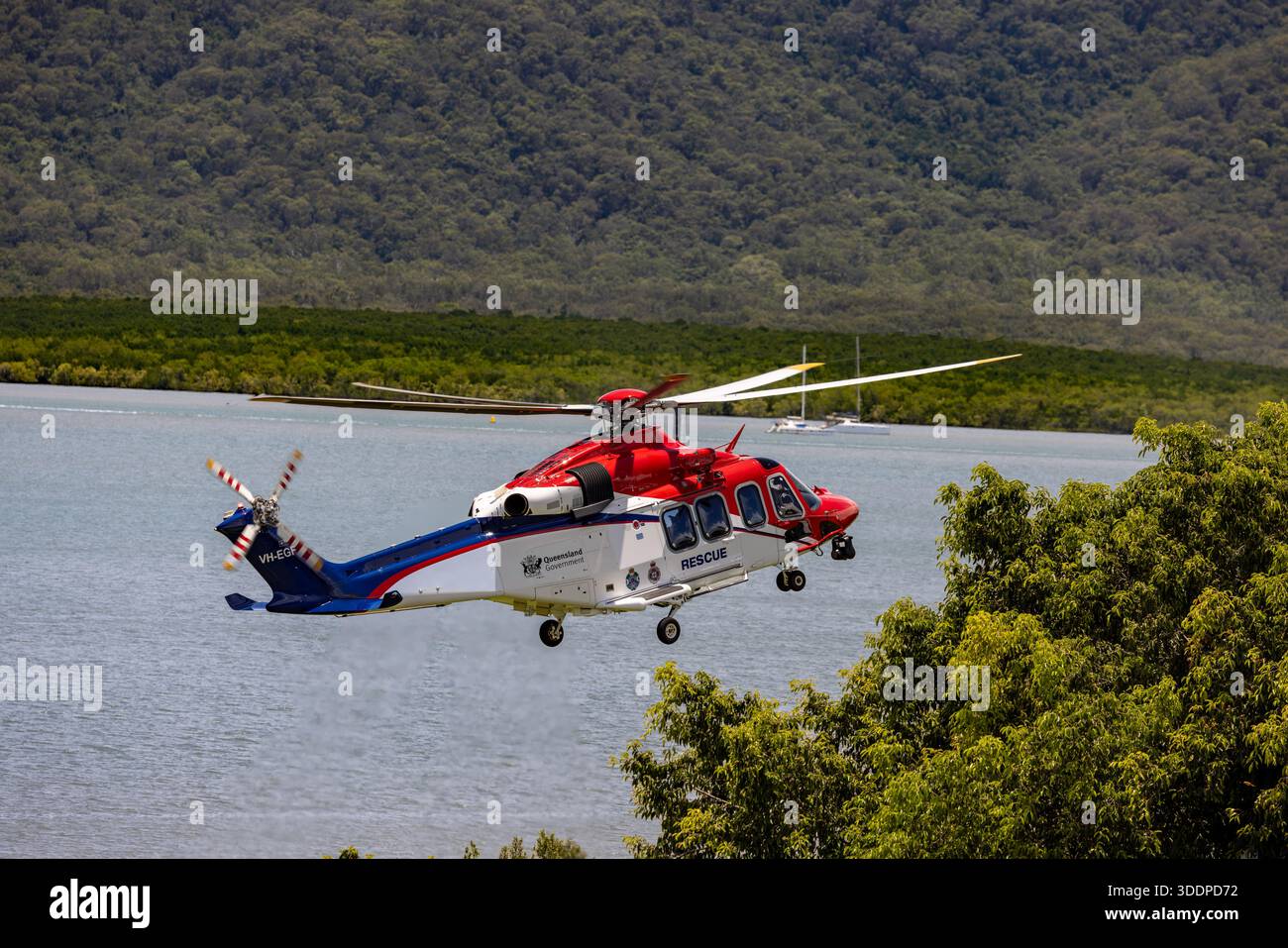 elicottero di salvataggio 510 vh-egf che si avvicina alla gamma di yarrabar degli alberi comunemente noto come murray prior range dietro durante l'atterraggio alla base di cairns hospit Foto Stock