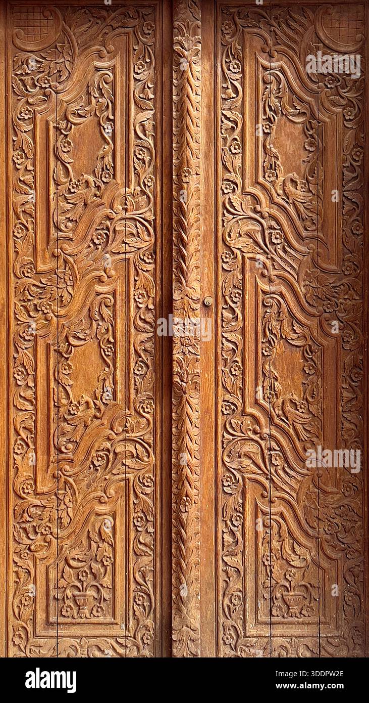 Porta in legno intagliato con motivi floreali scalpellati a mano e dettagli architettonici tradizionali Foto Stock