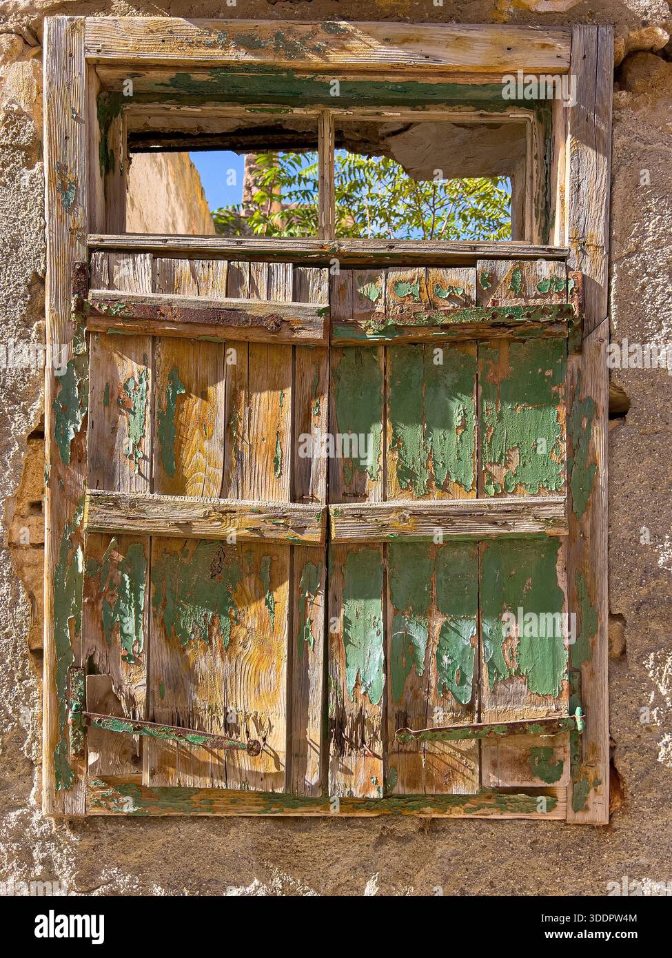 Vecchia cornice di legno per finestre e persiane sbriciolate su un muro in pietra invecchiata Foto Stock