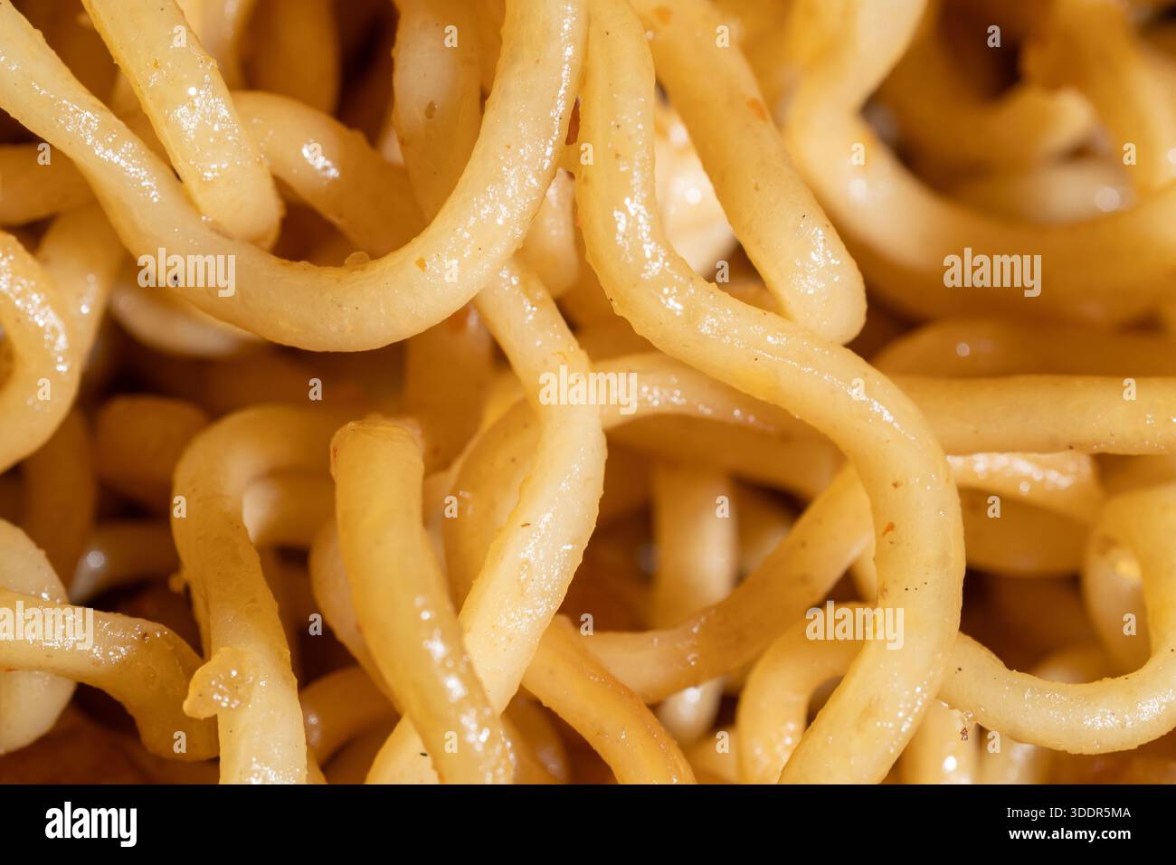 Primo piano di tagliatelle ricci gialle cotte. Delizioso sfondo con texture ramen per l'industria alimentare, il design del menu e la cucina asiatica. Foto Stock