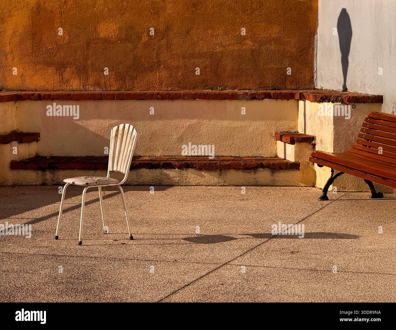 Sedia vuota e panchina gettano lunghe ombre su una terrazza tranquilla all'alba, Lisbona, Portogallo Foto Stock