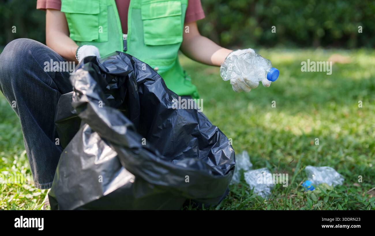 La persona raccoglie diligentemente le bottiglie di plastica gettate in un sacco per rifiuti. Questa scena mette in evidenza una gestione responsabile dei rifiuti e una dedizione all'ecologi Foto Stock