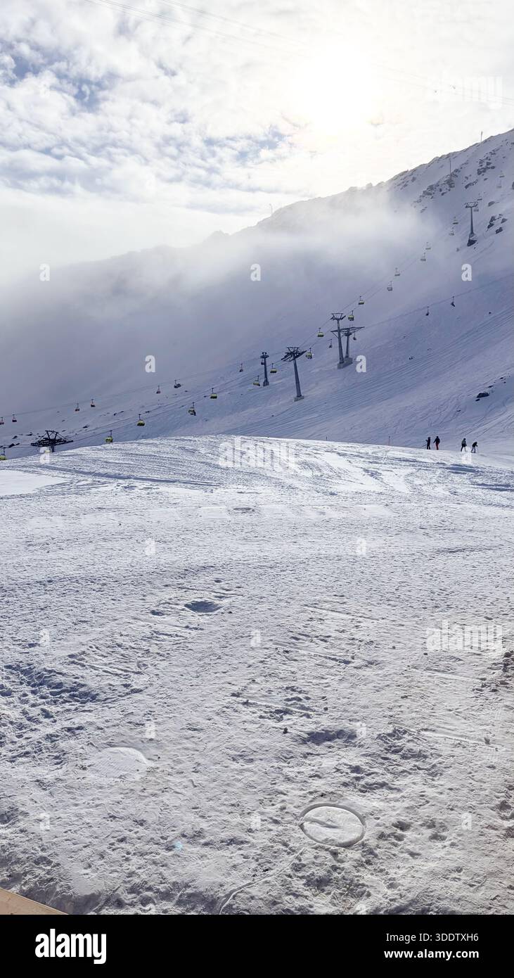 Pista da sci coperta di neve a Davos, Svizzera. Gli impianti di risalita con funi e seggiovie risalgono la montagna. Foto Stock