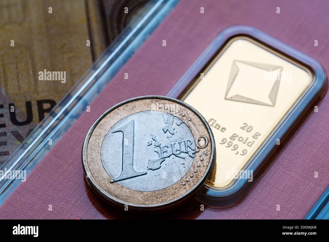 Gold bar con una moneta da euro in primo piano per copertura valutaria, volatilità del mercato e rifugio sicuro per metalli preziosi. Stafford, Regno Unito, 3 gennaio Foto Stock