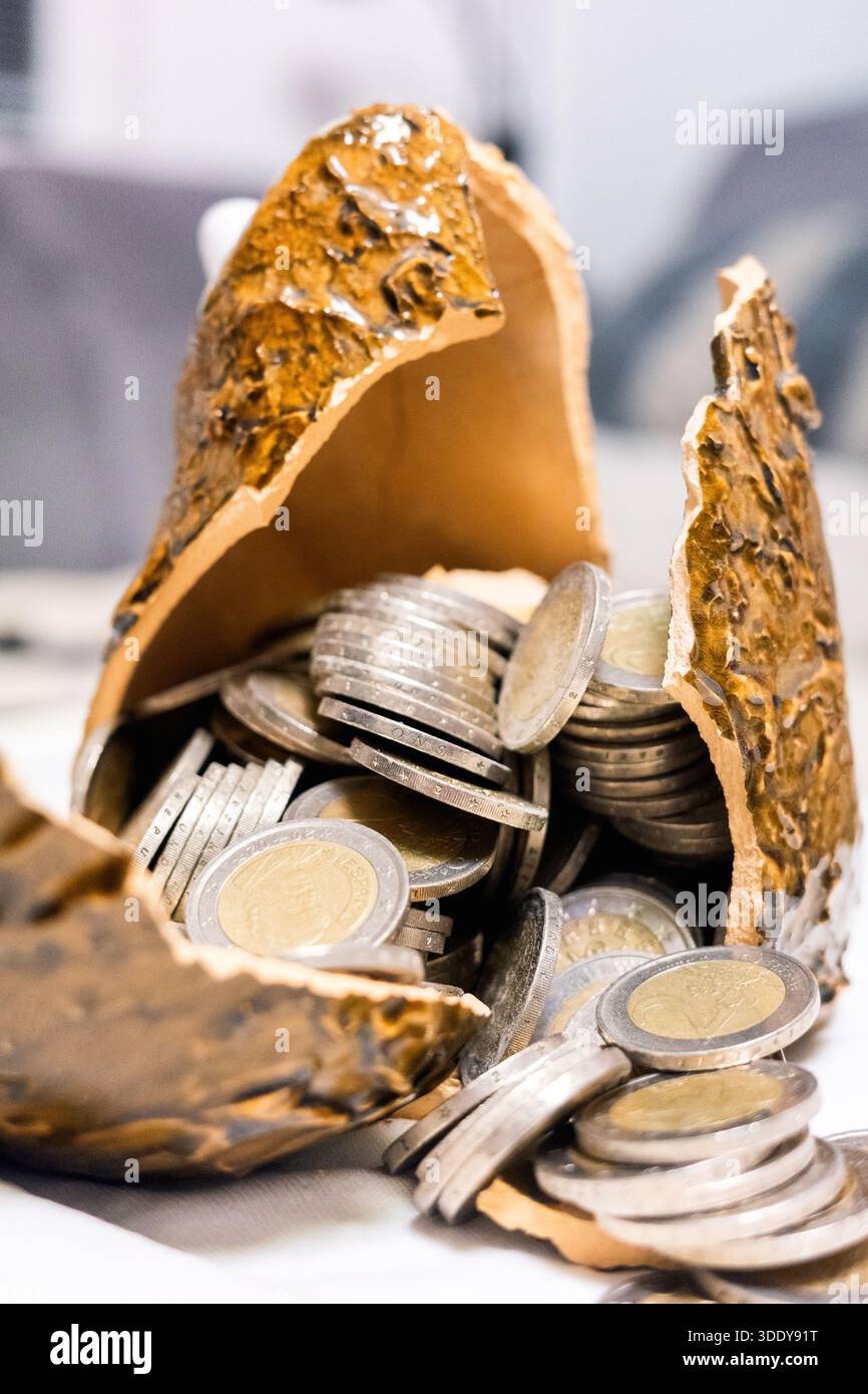 Vista ravvicinata del salvadanaio rotto pieno di monete in euro. Simbolo di risparmi falliti, problemi finanziari, pressione economica, impatto sull'inflazione e denaro Foto Stock
