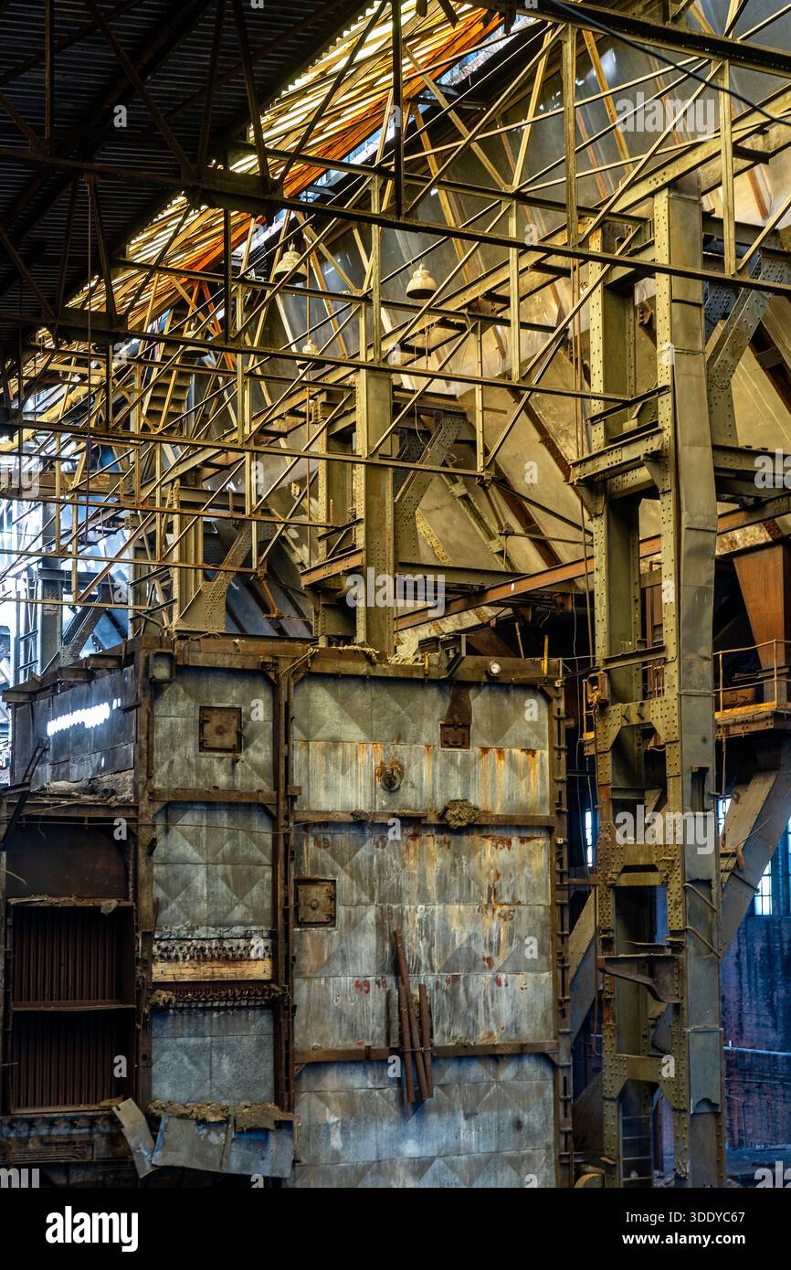 Grandi macchinari industriali abbandonati con pannelli metallici telai in acciaio e segni di deterioramento a lungo termine Foto Stock