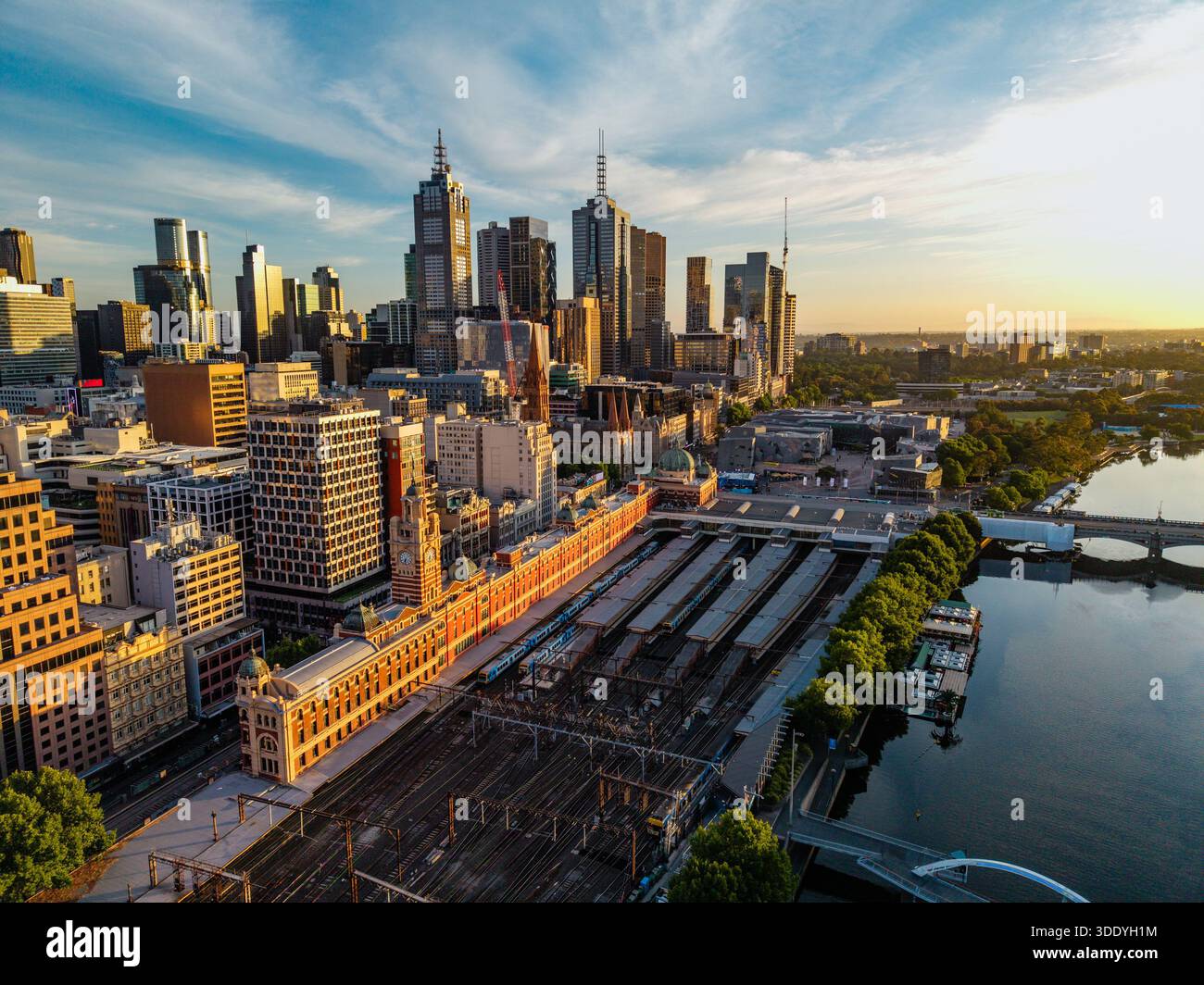 Una prospettiva aerea cattura il quartiere centrale degli affari di Melbourne durante l'ora d'oro, con la stazione di Flinders Street, i grattacieli e lo Yarra Foto Stock