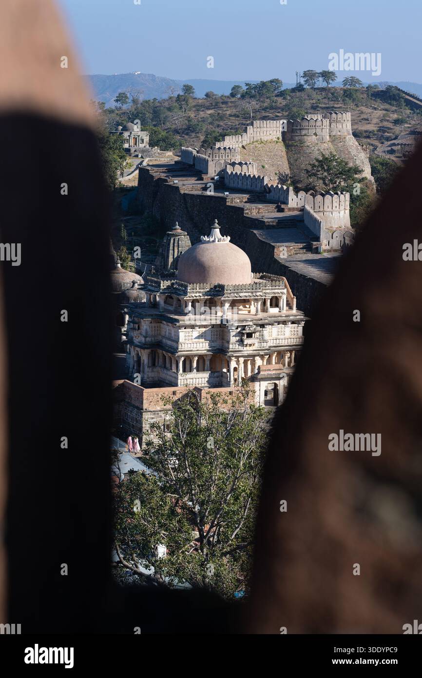 Ammira attraverso un abbraccio di alcuni dei templi del forte di Kumbhalgarh e delle sue grandi mura. Preso in una giornata di sole senza persone riconoscibili. Foto Stock