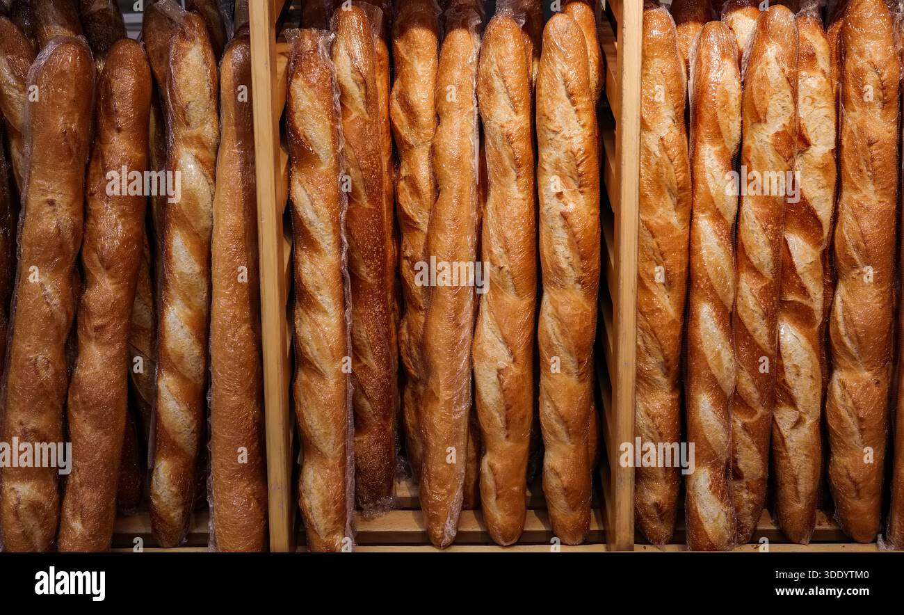Una fila di pani è esposta in una cassa di legno. I pani sono tutti marroni e sembrano essere appena sfornati. Foto Stock