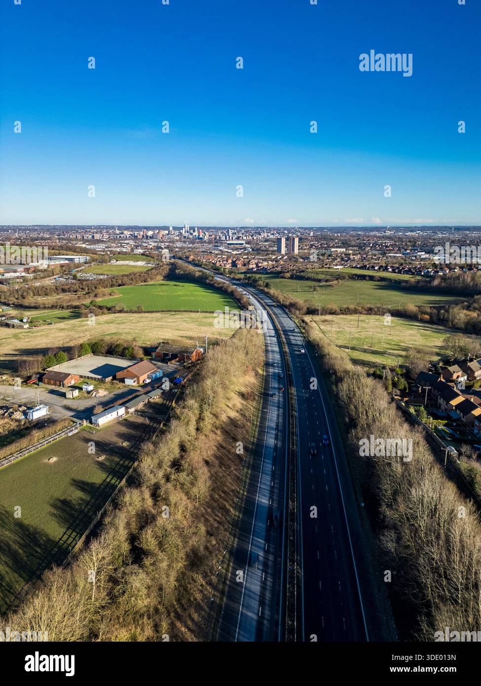 Vista aerea sull'autostrada M621 verso lo skyline del centro di Leeds, con cintura verde circostante e alloggi periferici nel West Yorkshire, Regno Unito Foto Stock