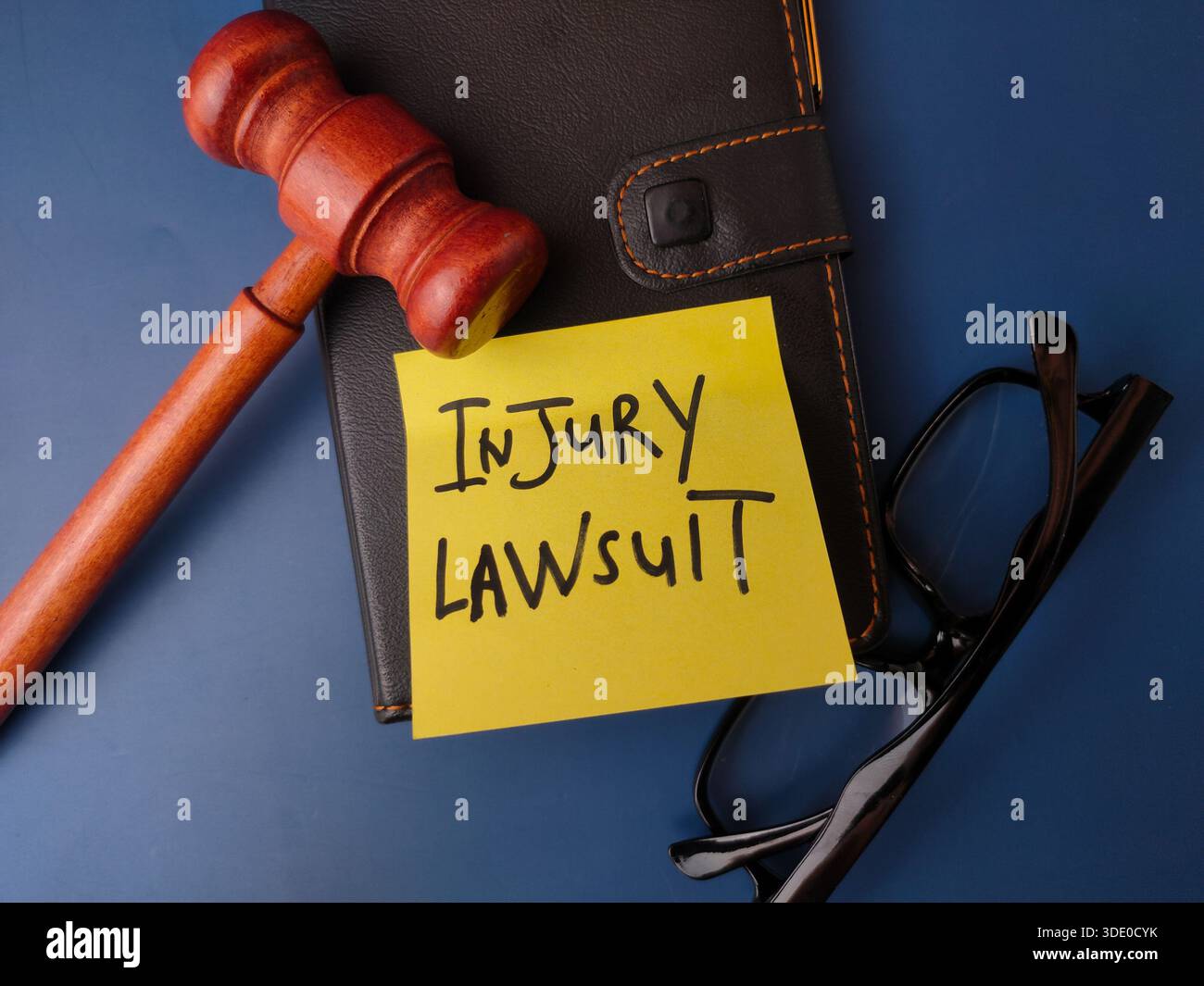 L'immagine mostra un concetto legale rappresentato da un martelletto, occhiali, notebook e una nota adesiva con il testo CAUSA PER INFORTUNIO. Foto Stock
