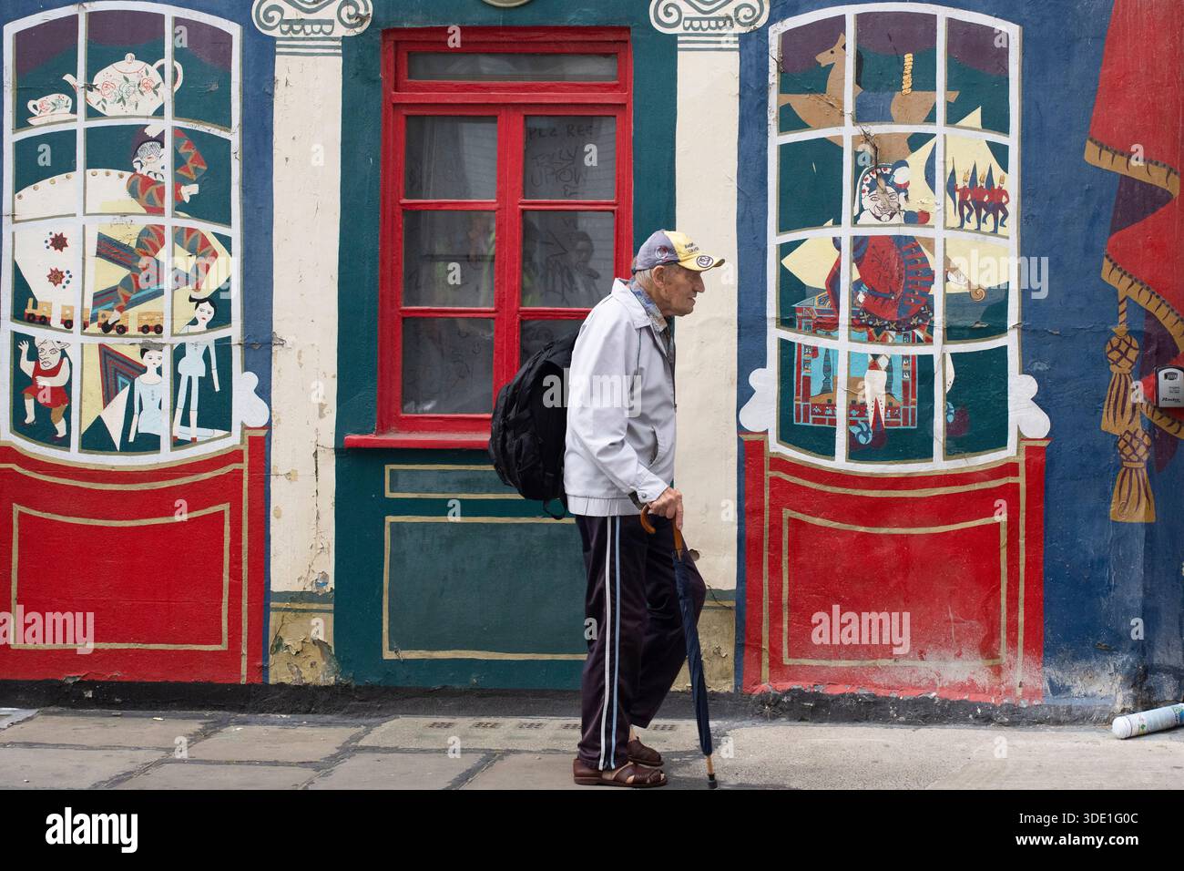 Un uomo anziano passa davanti a un vivace murale di un edificio a Londra Foto Stock