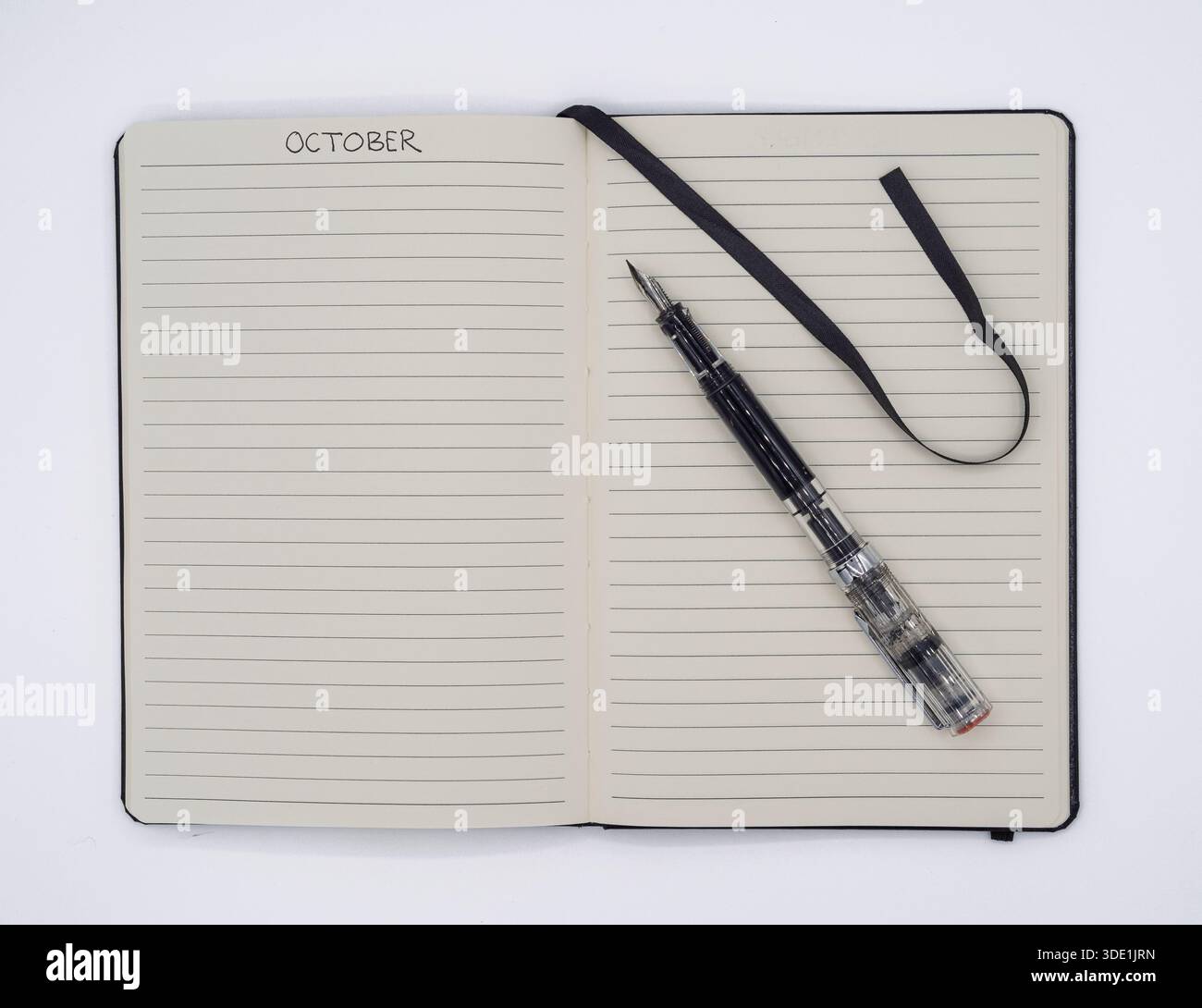Vista dall'alto di un notebook aperto fino a ottobre con una penna stilografica trasparente, perfetta per la pianificazione dei programmi autunnali. Foto Stock