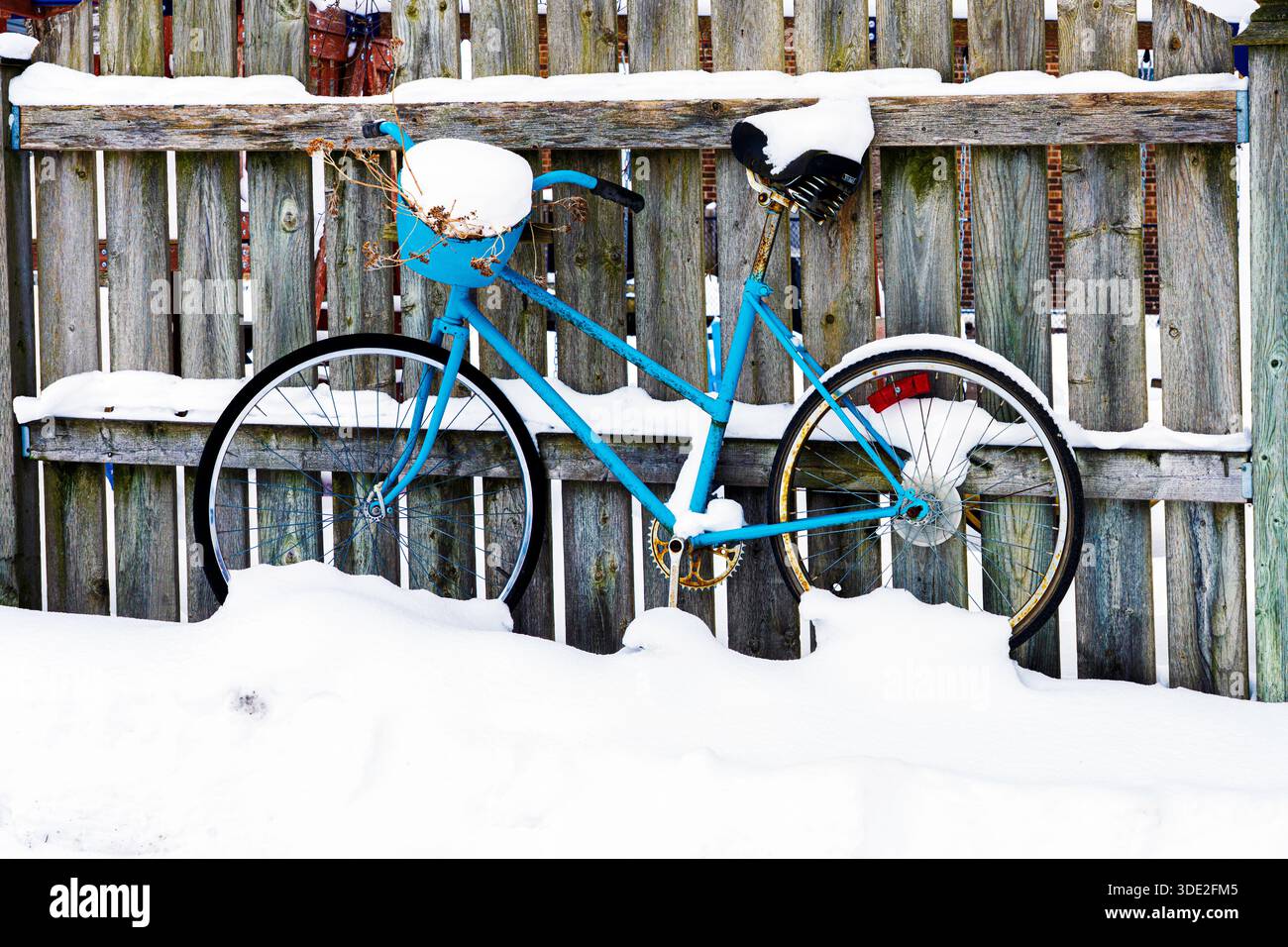 Bicicletta blu appoggiata contro una recinzione coperta di neve a Seaforth Ontario. 4 gennaio 2026. Foto Stock