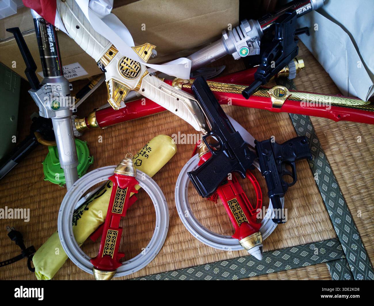 SAITAMA, GIAPPONE - 01 GENNAIO 2026: Armi giocattolo Sentai di plastica sparse su un tappetino Tatami, cimeli nostalgici dell'era Heisei giapponese. Foto Stock