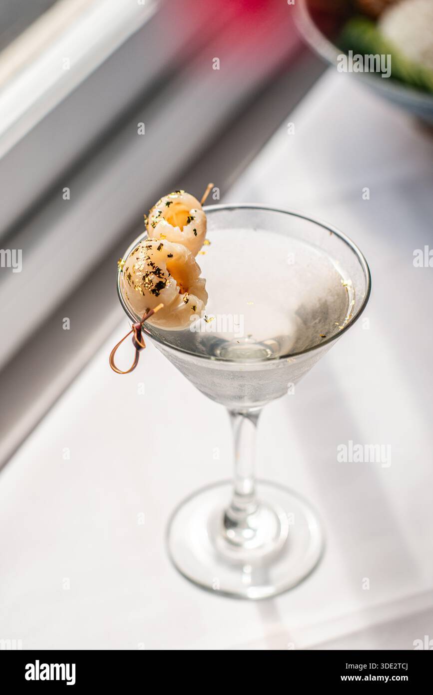 Elegante cocktail martini al litchi servito in un classico bicchiere di martini, con vodka, liquore al litchi e succo di litchi. Foto Stock
