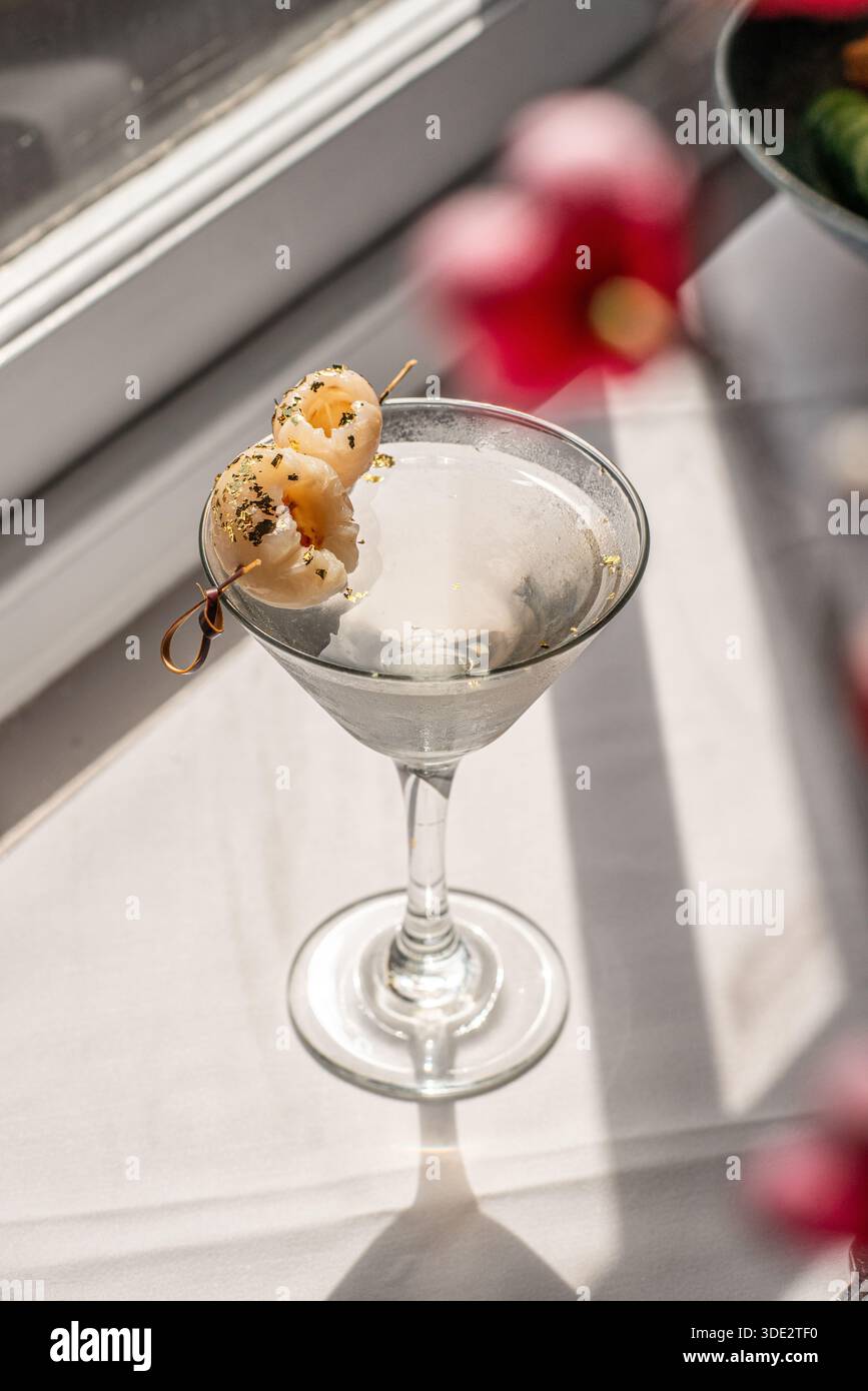 Elegante cocktail martini al litchi servito in un classico bicchiere di martini, con vodka, liquore al litchi e succo di litchi. Foto Stock