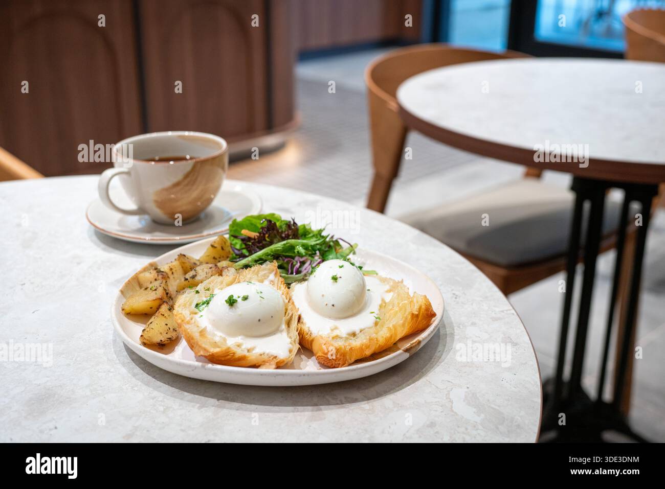 Colazione Benedict con uova e tazza di caffè in un ristorante. Foto Stock