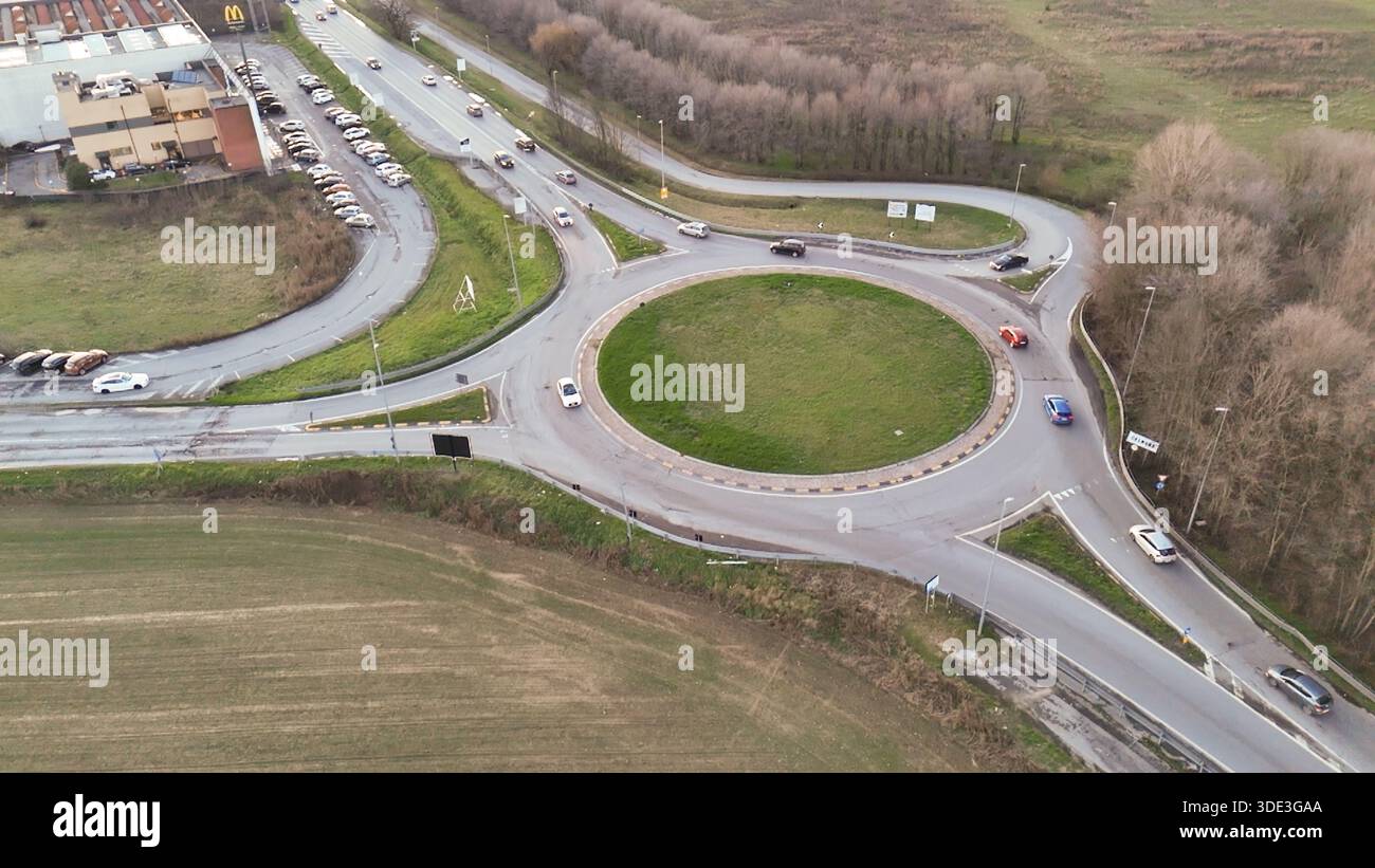 Una prospettiva dall'alto cattura i veicoli che si muovono attraverso una rotatoria a più corsie, mostrando le infrastrutture urbane e le dinamiche dei trasporti Foto Stock