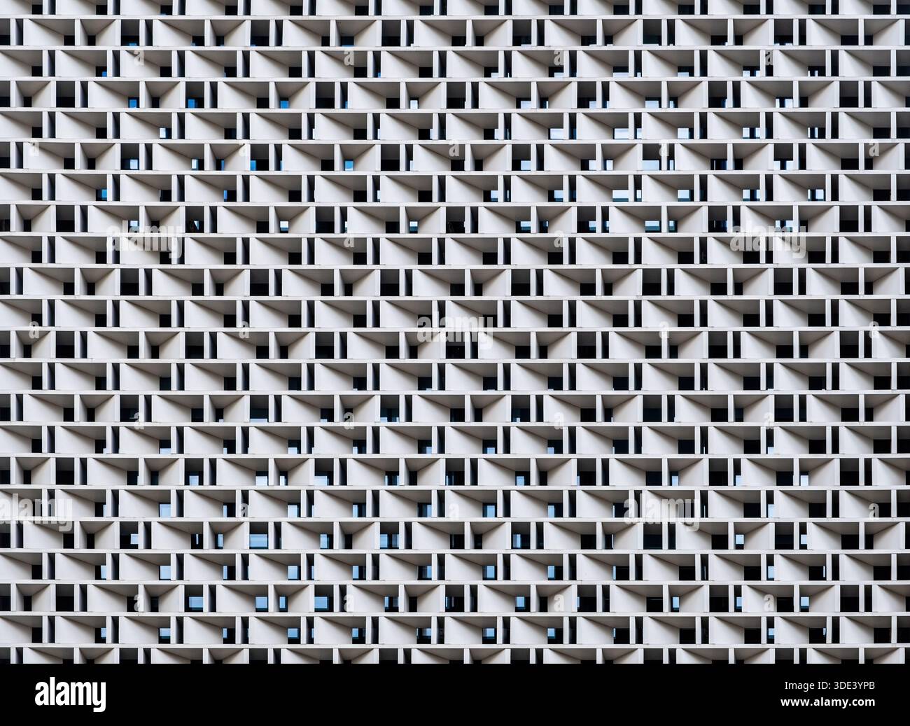 un'alta facciata modernista che presenta un modello ripetitivo di sporgenze geometriche, triangolari e rettangolari, cemento e acciaio, creando una Foto Stock