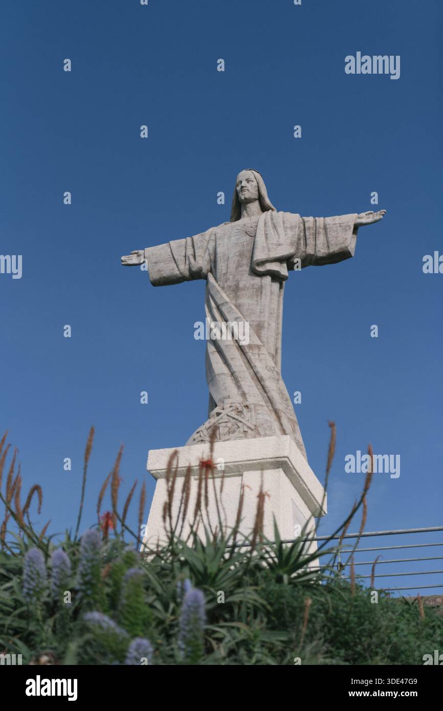 Statua del Cristo Re a Garajau, Madeira, con cielo blu e fiori Foto Stock