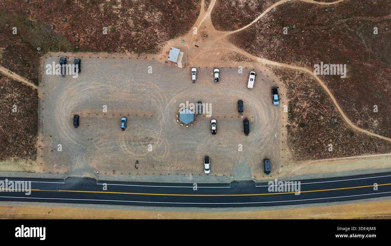 Vista aerea delle auto parcheggiate in una sosta nel deserto vicino a un'autostrada, il paesaggio un arazzo di marrone terroso e verdi tenui, Fruita, Colorado, United Foto Stock