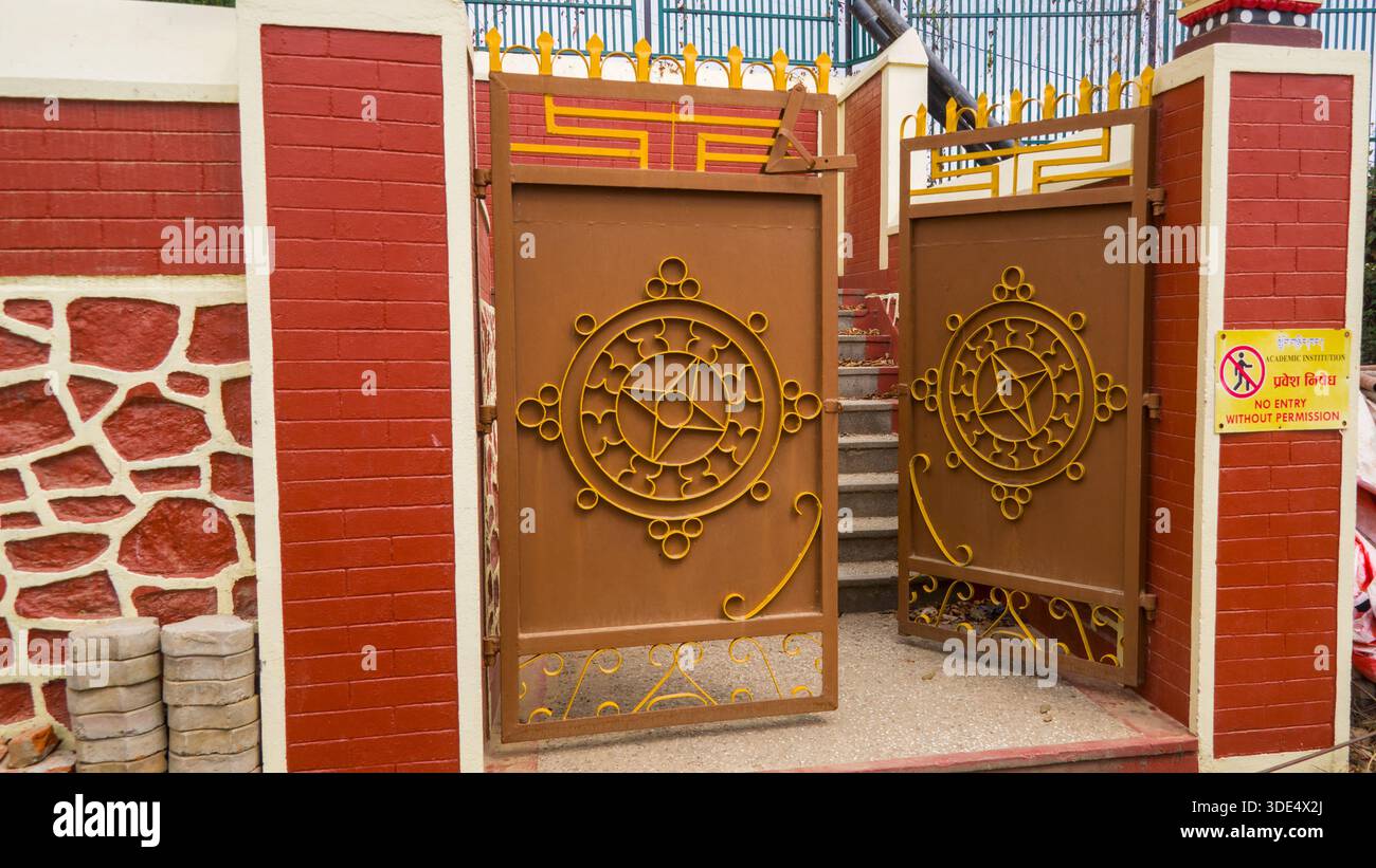 Un cancello marrone decorato in modo elaborato con elementi adornati di giallo, incorniciato all'interno di una struttura a parete rossa, che mostra l'artigianato tradizionale. Foto Stock