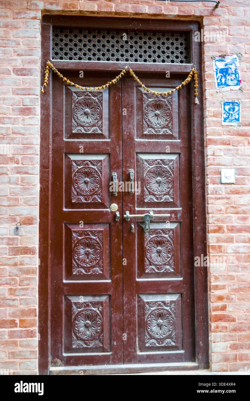 Una porta chiusa in legno con intricati motivi decorativi e ornamenti in metallo in uno stile architettonico tradizionale. Foto Stock