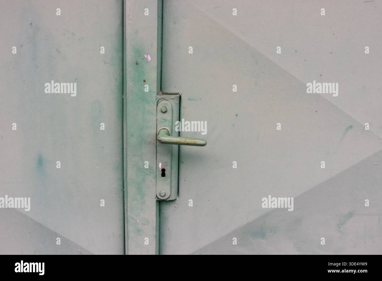 Maniglia della portiera in metallo verde resistente agli agenti atmosferici e foro per chiave con vernice usurata e texture industriale Foto Stock