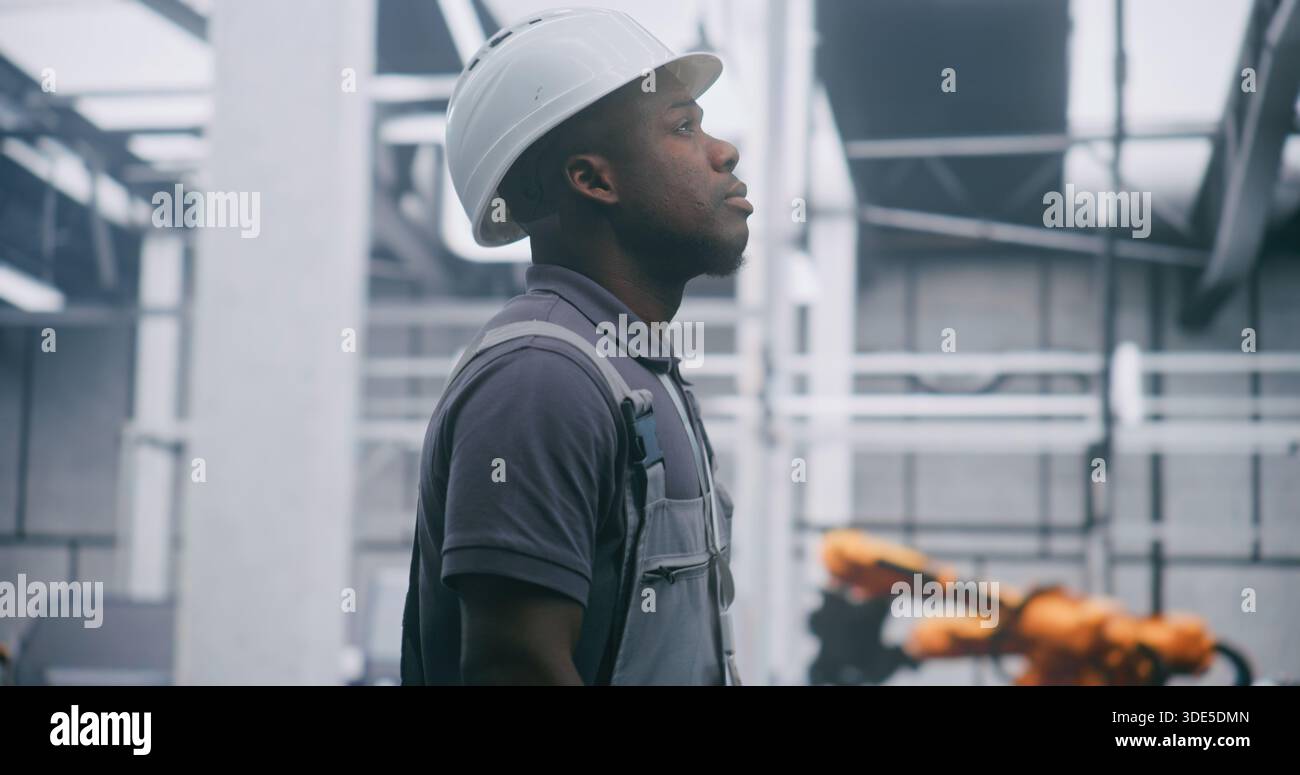 Focused Factory Engineer fornisce sistemi industriali di monitoraggio professionali in elmetto e tute di sicurezza con espressione seria. Responsabilità concettuale per il monitoraggio di sistemi industriali complessi. Foto Stock