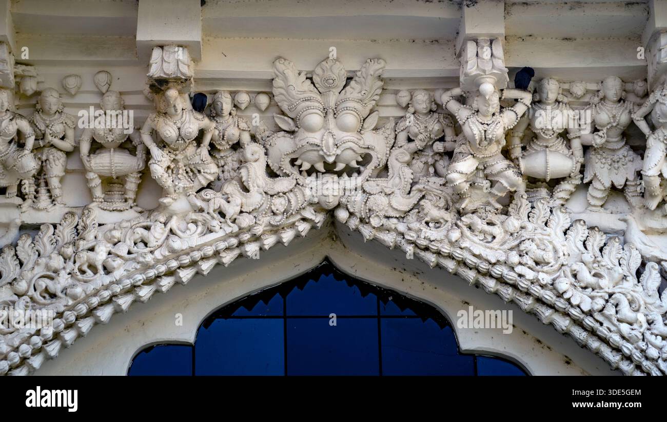Intricate incisioni in pietra bianca su una facciata del tempio con figure mitologiche. Foto Stock