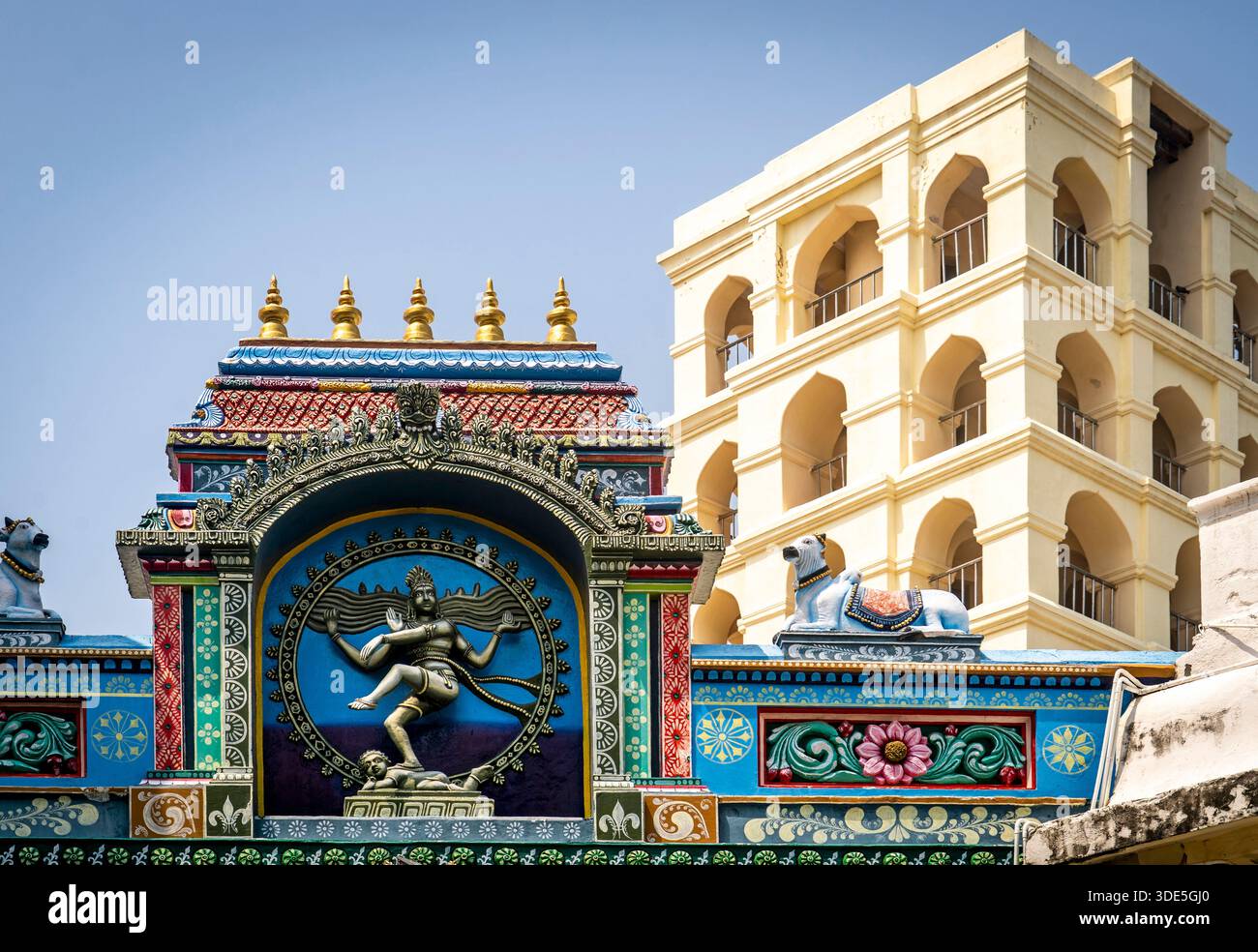 Colorata facciata del tempio indù con intricate incisioni e un edificio moderno sullo sfondo. Foto Stock