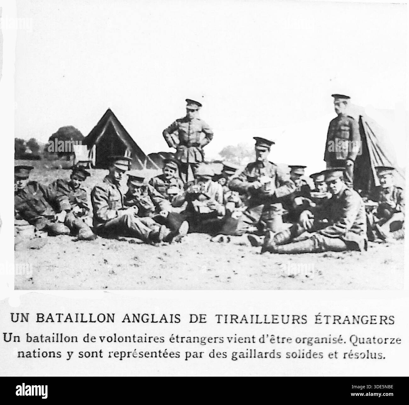 Questa fotografia d'archivio del 1914 di le Miroir presenta un battaglione di volontari stranieri organizzati all'interno dell'esercito britannico. Rappresentando quattordici nazioni diverse, questi "compagni solidi e risoluti" sono mostrati riposare in un campo improvvisato durante le prime fasi della prima guerra mondiale. L'immagine mette in evidenza la portata globale della mobilitazione e il diverso sostegno internazionale alla causa alleata, mostrando l'unificazione di individui di varie origini per sostenere le forze britanniche durante i mesi iniziali della grande Guerra. Foto Stock