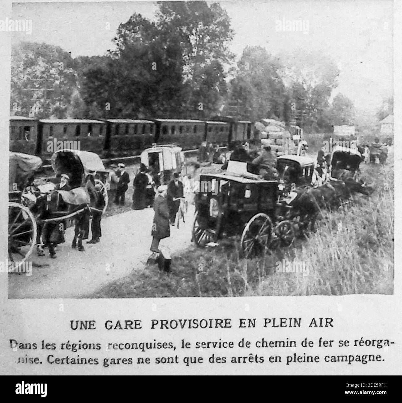 Questa fotografia d'archivio del 1914 di le Miroir illustra le sfide logistiche della grande Guerra nei territori francesi riconquistati. Con lo spostamento delle linee del fronte, il servizio ferroviario faticò a riorganizzarsi, portando alla creazione di stazioni provvisorie in campi aperti. L'immagine mostra un treno fermo in campagna, dove carrozze trainate da cavalli e passeggeri si incontrano in un hub di transito improvvisato. Sottolinea la resilienza delle infrastrutture e gli sforzi immediati per ripristinare i collegamenti di trasporto vitali nel caos del conflitto. Foto Stock