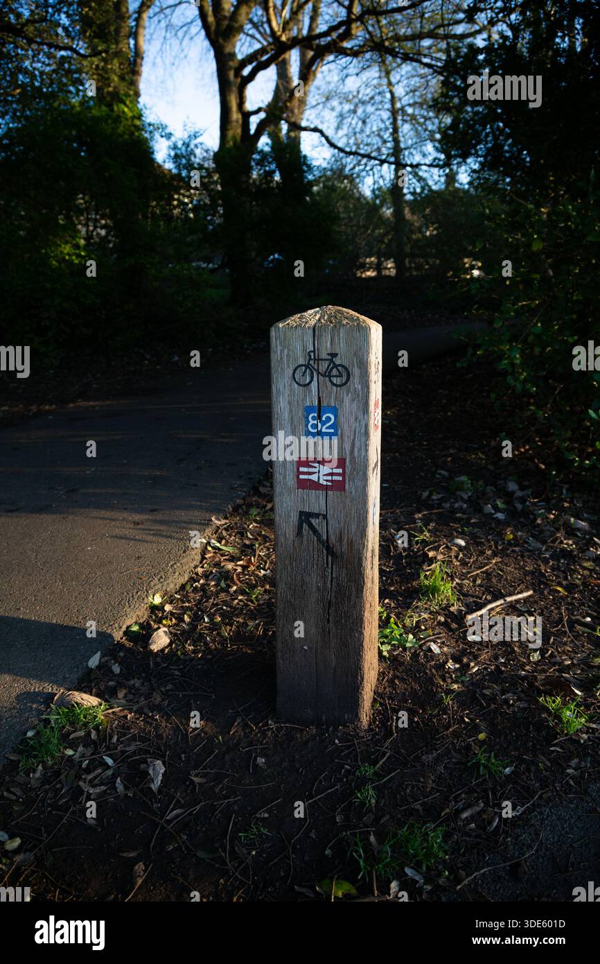 Posto di rovere / segnavia per NCN / National Cycle Network a Hove Park, Brighton, che mostra le indicazioni per la stazione ferroviaria in un giorno di sole inverno Foto Stock