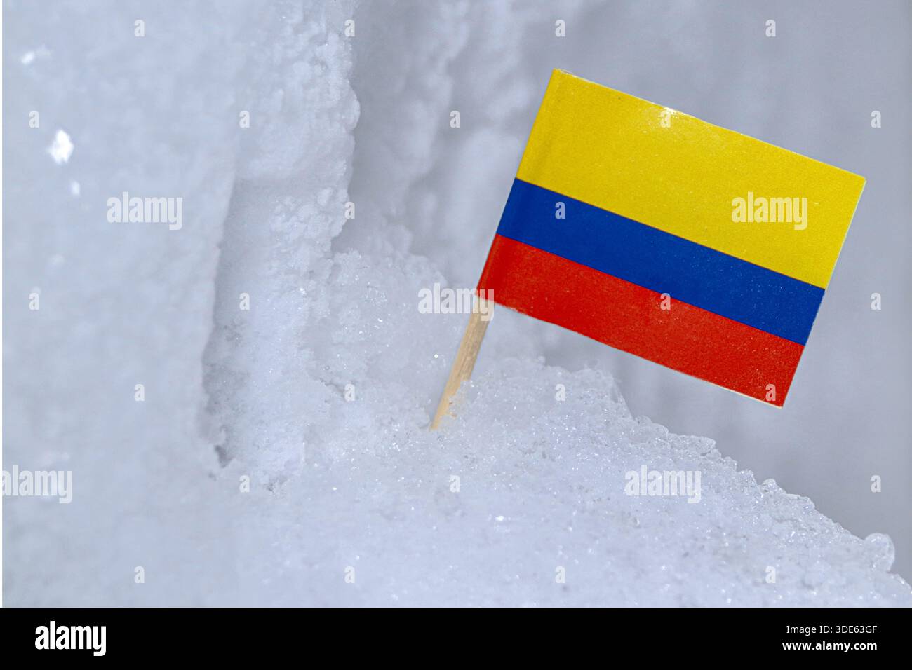 Bandiera nazionale colombiana in piedi sulla neve e sul ghiaccio, simboleggia il cambiamento climatico, le rare condizioni invernali e i modelli meteorologici inaspettati. Foto Stock