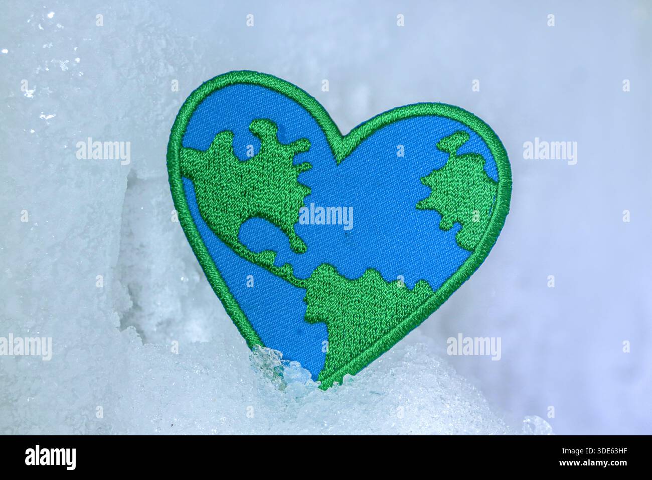 Mappa della terra a forma di cuore su neve ghiacciata. Metafora visiva per l'emergenza climatica, la fragilità ambientale e gli sforzi di conservazione globale per le ONG. Foto Stock