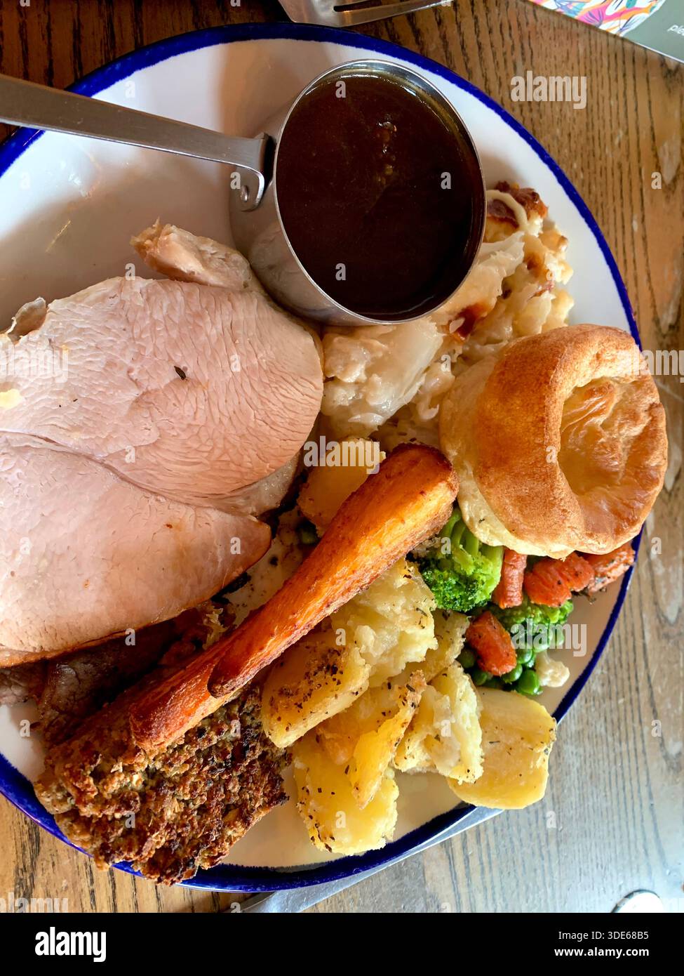 Cena tradizionale britannica con arrosto servita su un piatto bianco con bordo blu con pollo arrosto budino dello Yorkshire verdure arrosto purè di patate - Immagine stock catturata con smartphone